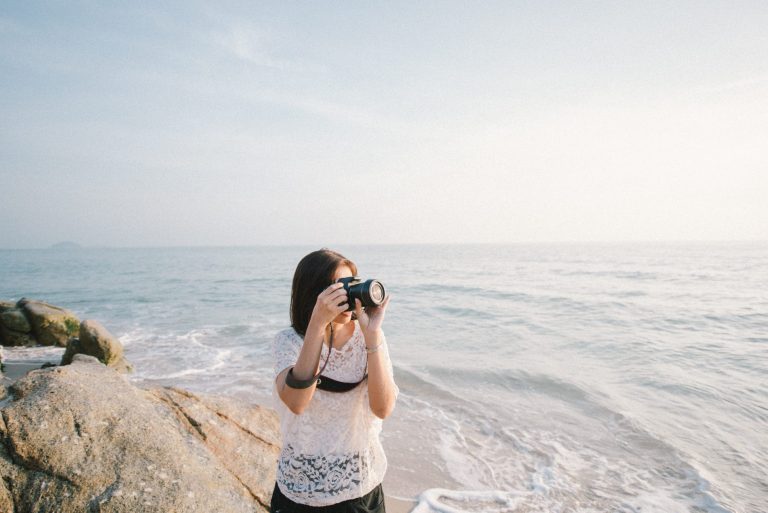 A woman capturing the mesmerizing ocean view with her camera, contributing to the collection of stock images.