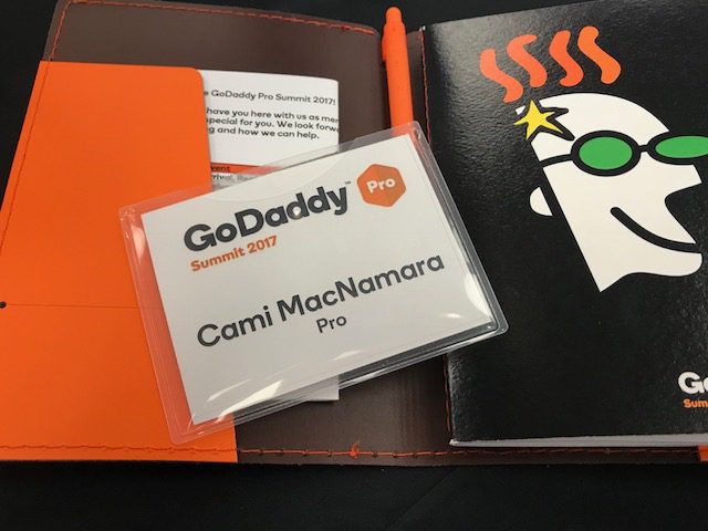 A notebook featuring an orange cover and a pen positioned on top, used during the GoDaddy Pro Summit 2017.