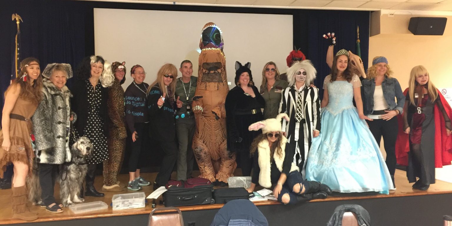 A group of people dressed up in Halloween costumes posing for a picture.