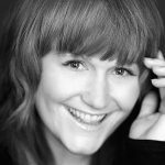 A black and white photo of a woman smiling, who happens to be a web designer from West Seattle.